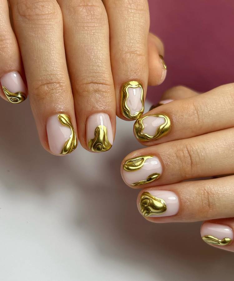 Unhas curtas esmaltadas em nude com detalhes abstratos dourados em relevo, criando um visual moderno e sofisticado. O design brilhante destaca-se contra o fundo suave, transmitindo elegância e originalidade na arte das unhas.






