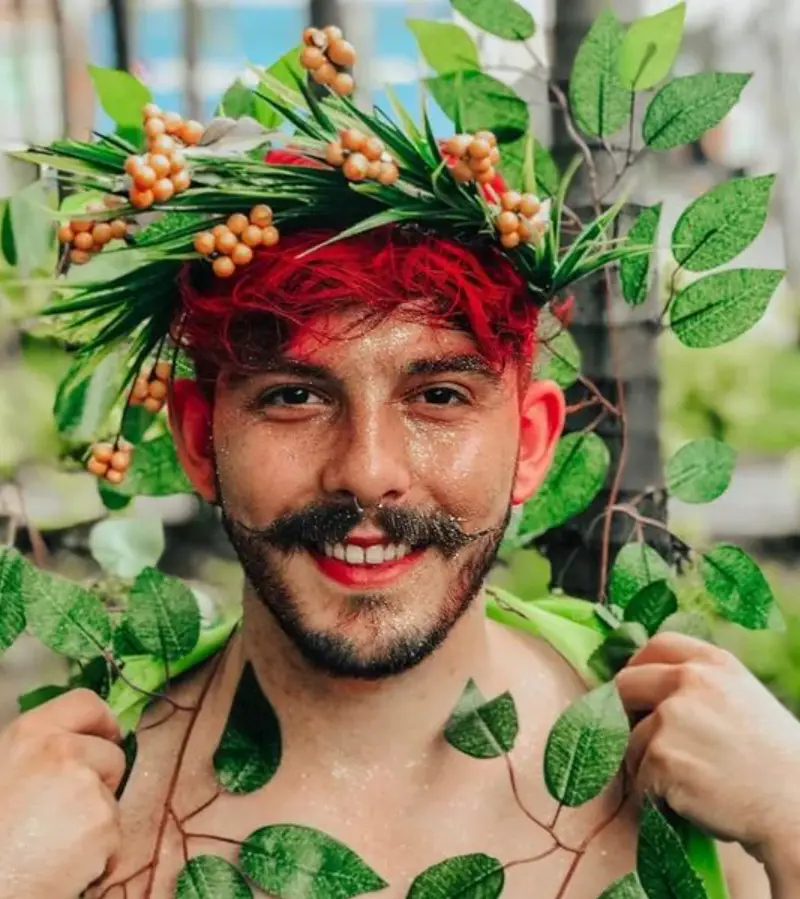 Homem de pele clara com fantaia de planta e glitter no rosto