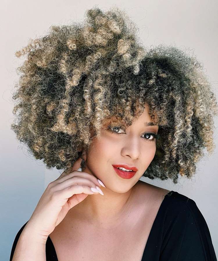 Mulher com cabelo crespo castanho iluminado, curto e repicado