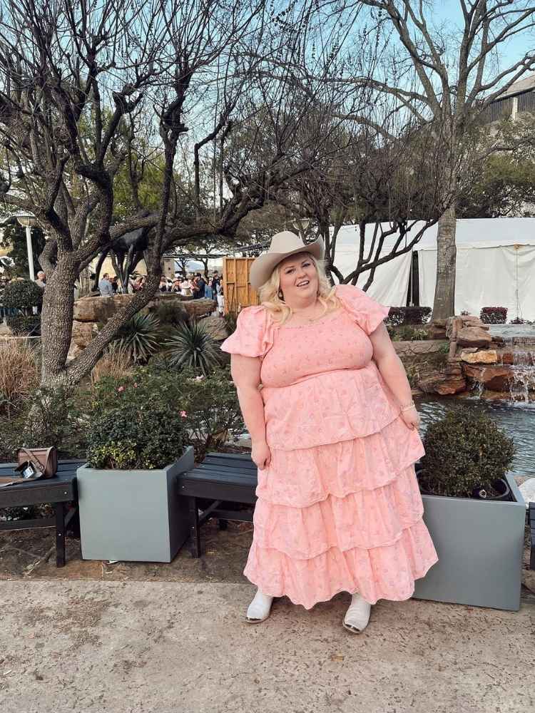 Mulher de pele clara usando vestido rosa claro com babados