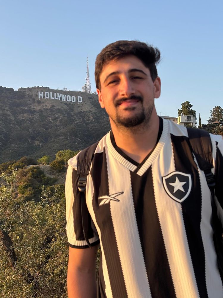 Daniel Braune usando camisa do Botafogo com letreiro de Holywood ao fundo 