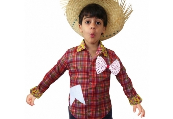 Menino com camisa xadrez vermelha, com laço e bandeirinha, além de chapéu de palha