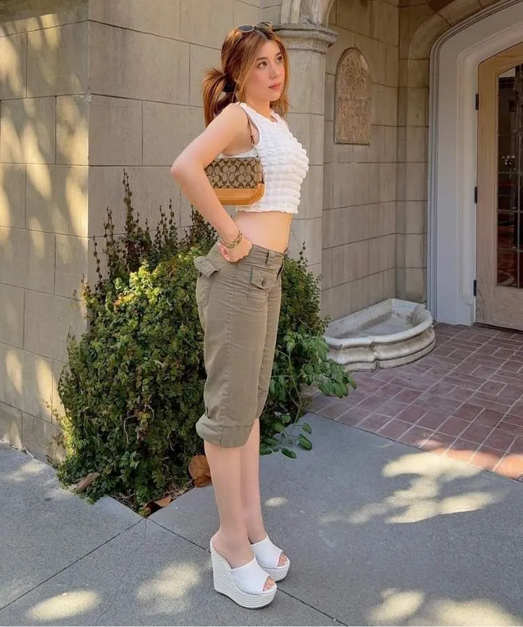 Mulher usando top branco, calça capri cáqui e tamanco de salto anabela branco