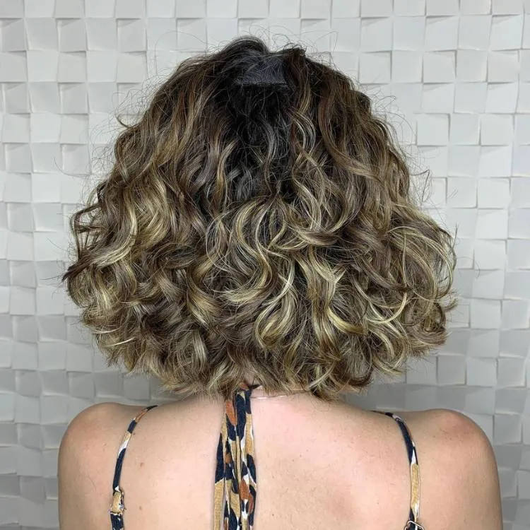 Mulher de pele clara de costas com cabelo chanel cacheado