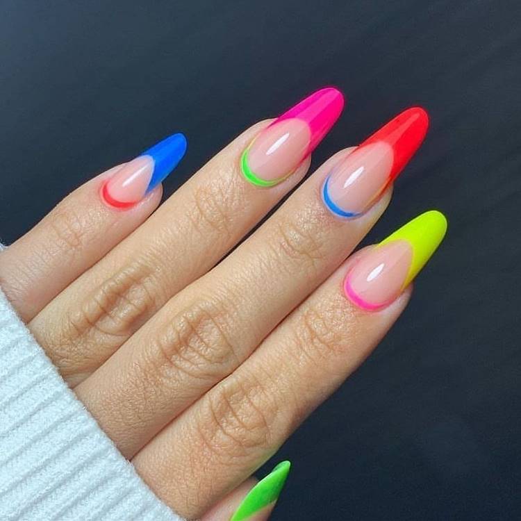 Mão com unhas arco-íris LGBTQIA+: Polegar: com francesinha verde neon e cutícula pink Indicador: Médio: nude com francesinha amarela e cutícula pink Anelar: com francesinha vermelha e cutícula azul nude com francesinha pink e cutícula verde non Mínimo nude com francinha azul e cutícula vermelha