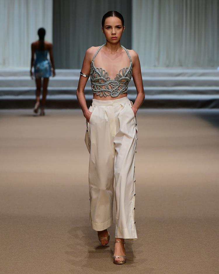 modelo com conjunto de top bordado e calça branca.