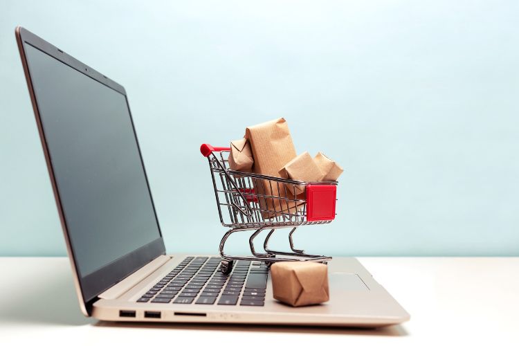 notebook aberto com pequeno carrinho e compras em cima: compras internacionais passam a ser taxadas