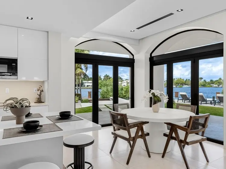 Nova mansão de Gusttavo Lima vista por dentro, cozinha com mesa redonda, ilha e vista para mar do lado de fora