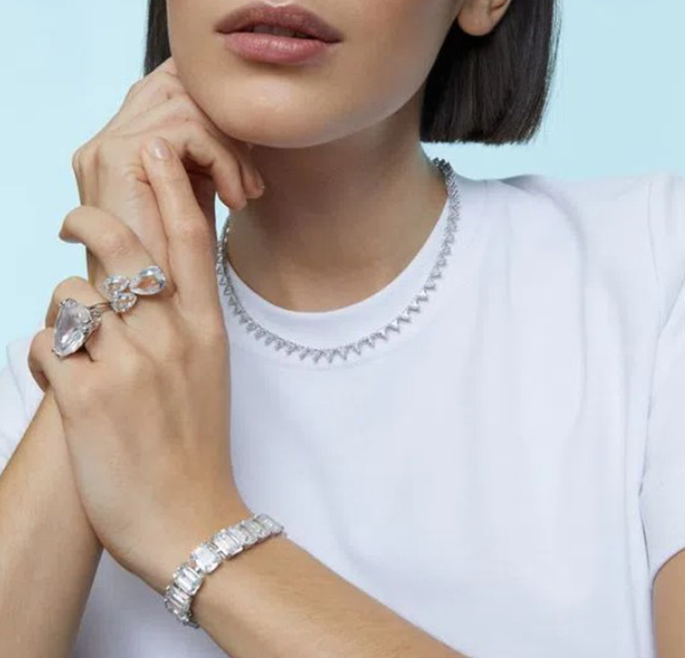 Foto de uma mulher usando dois aneis e uma pulseira de cristais brancos.