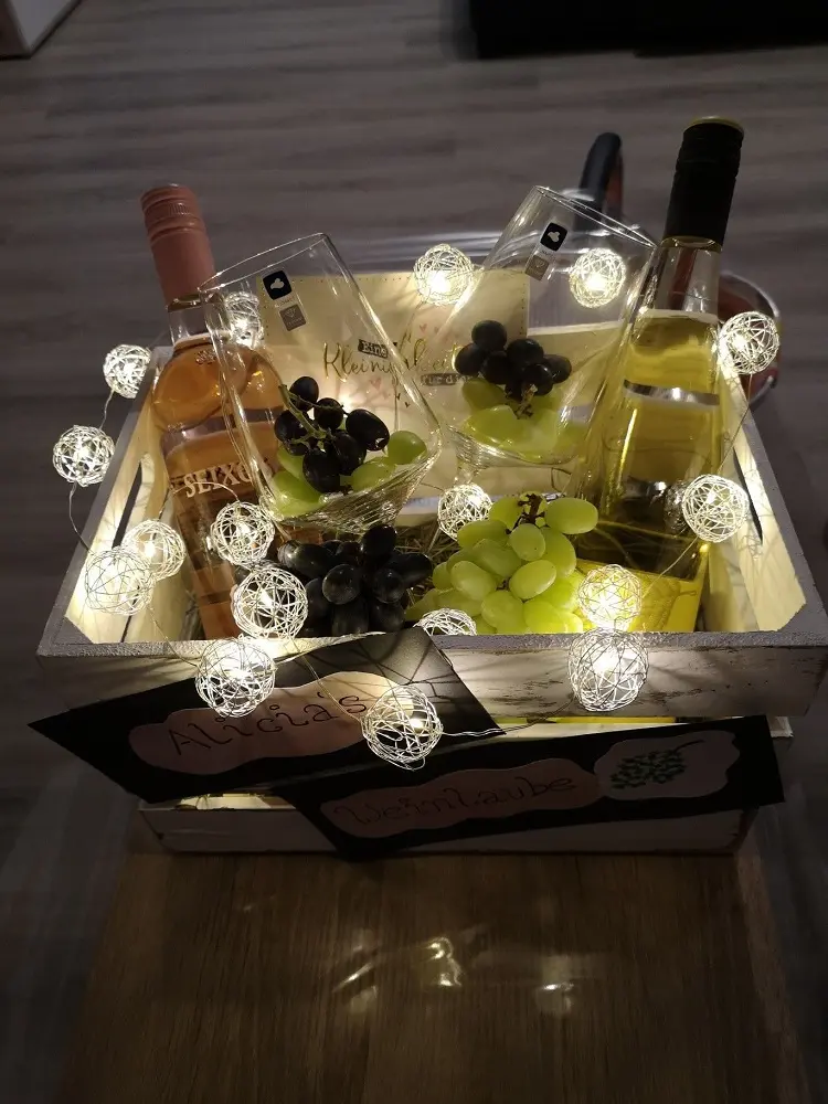 caixa com vinhos, taças, uvas e luzes