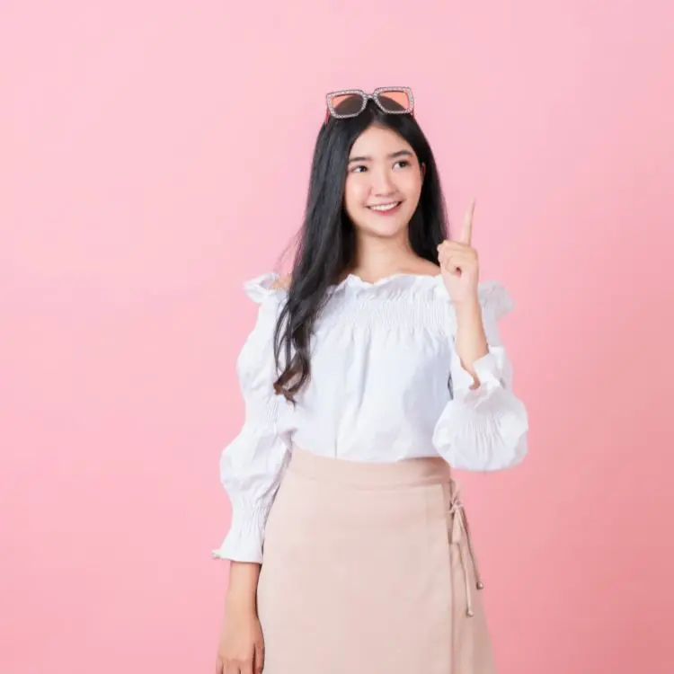 Mulher asiática usando camisa branca e saia rosa em fundo rosa