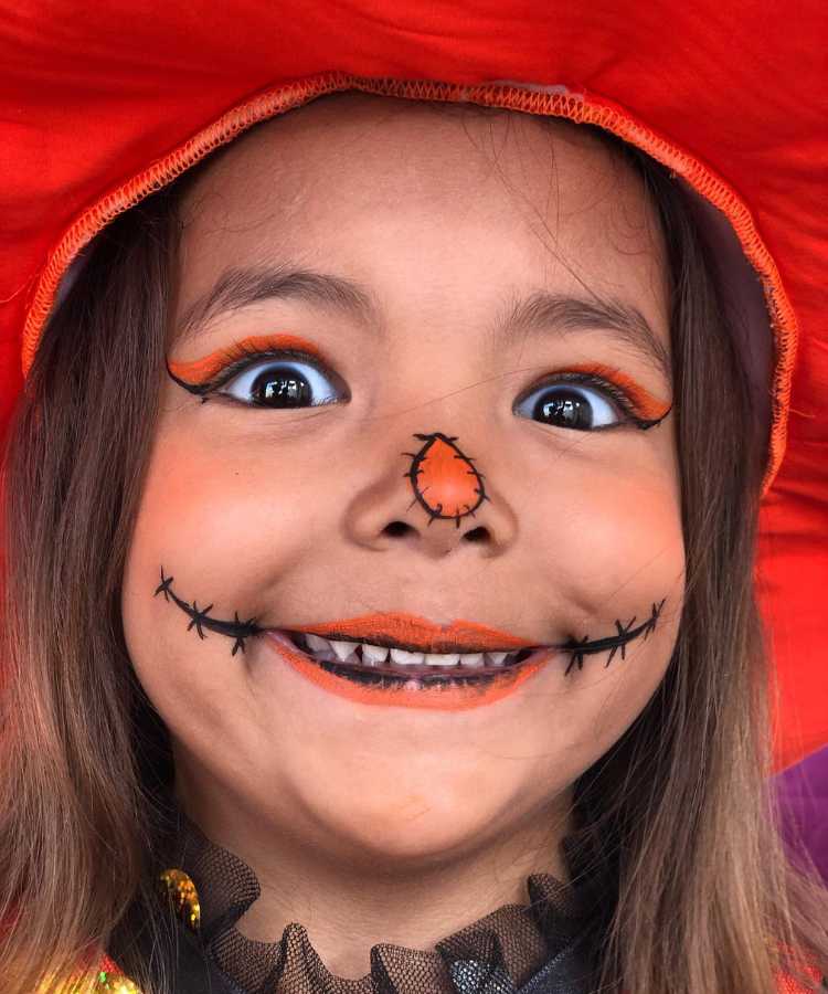 Garota maquaida de bruxa para o Halloween: Cores predominantes: preto e abóbora. Usa: make de cara de abóbora