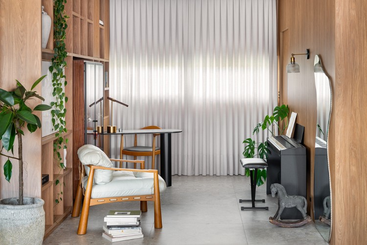 Home office com móvel solto, mesa, poltrona bege, piano e cortina 