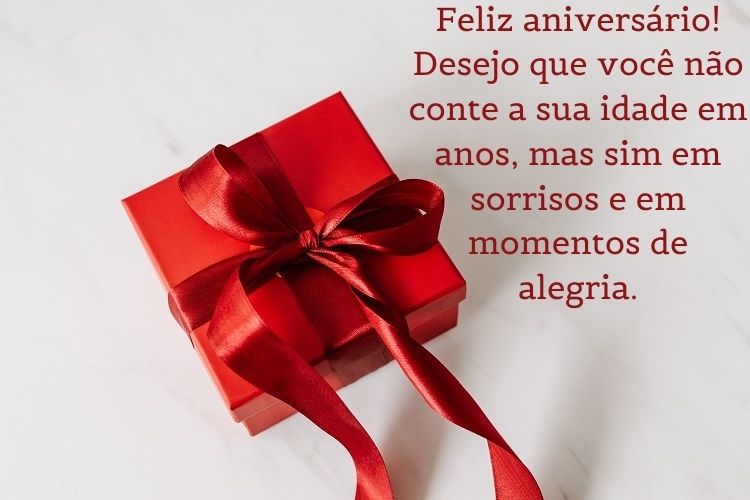 Fundo branco com embalagem de presente vermelha e frase "Feliz aniversário! Desejo que você não conte a sua idade em anos, mas sim em sorrisos e em momentos de alegria. "