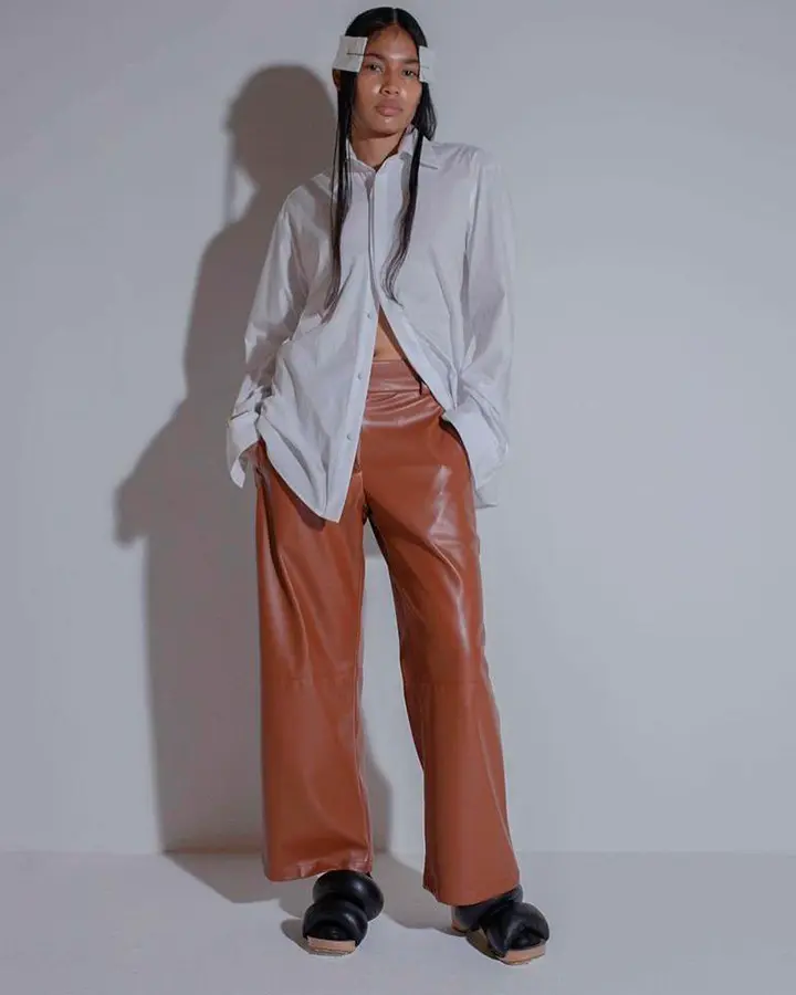 Modelo com calça marrom e blusa de botão branca