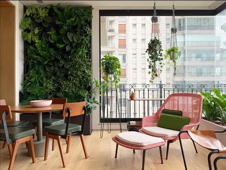 Jardim vertical em sala de jantar de prédio com plantas pendentes, mesa redonda e poltrona