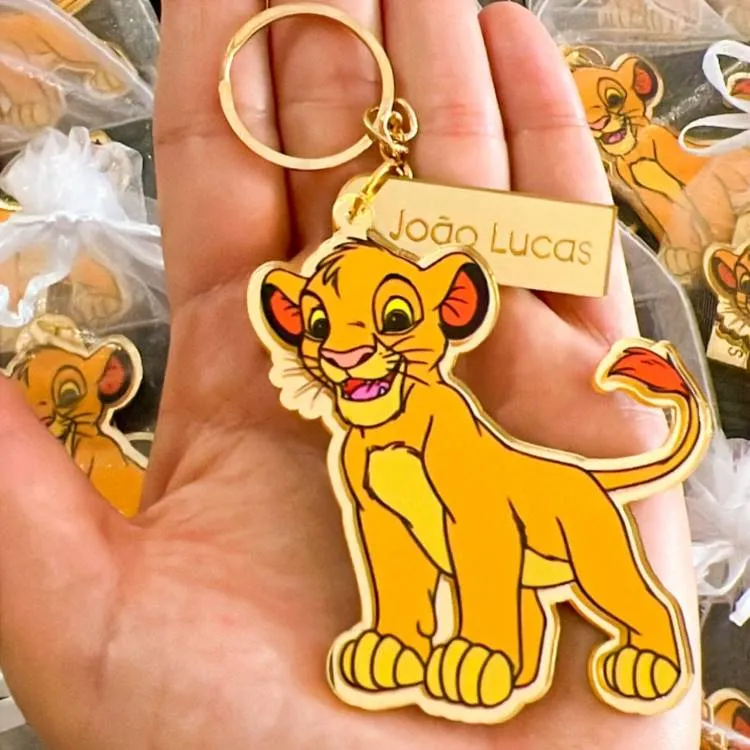 Um chaveiro dourado e em acrílico, com um design do personagem Simba, do filme O Rei Leão. O chaveiro tem uma pequena placa retangular com o nome "João Lucas" gravado, tornando-o um presente personalizado.







