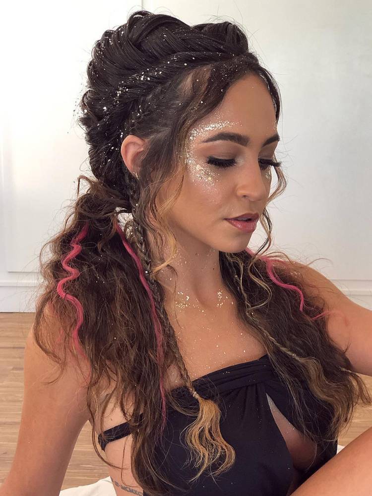 Mulher de pele clara com cabelo semi solto, com tranças, acessórios e brilho. 