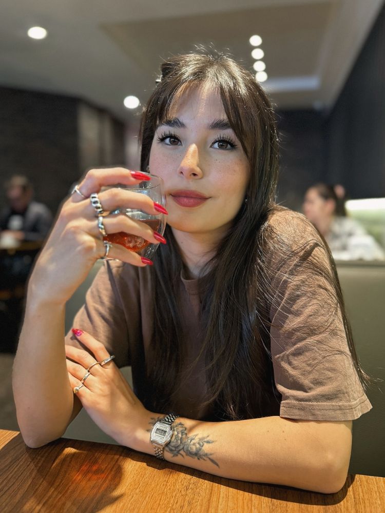 Victória Zattoni de blusa marrom tomando café