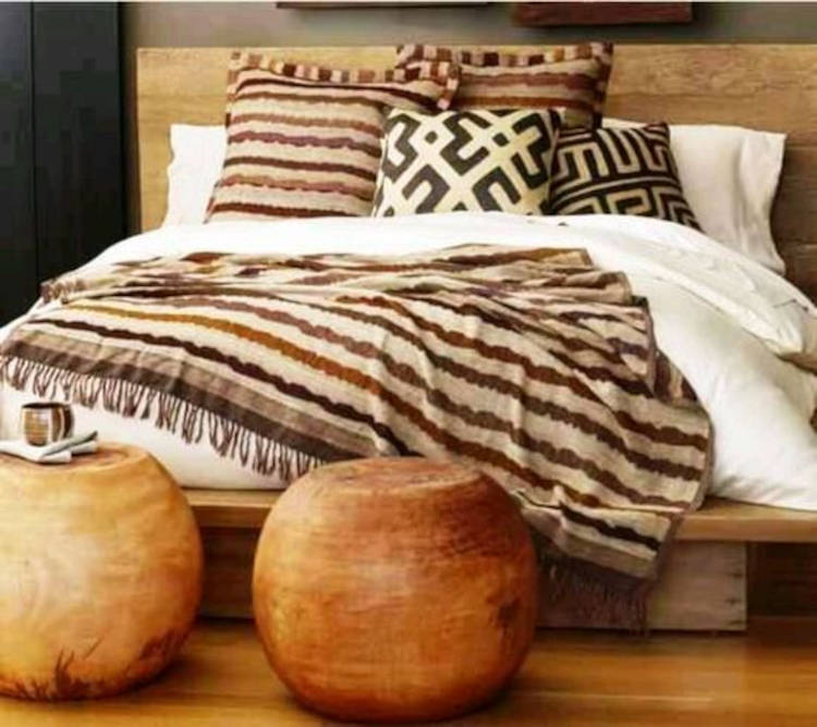 Cama de casal com roupa de cama off-white, almofadas e manta em tons terrosos