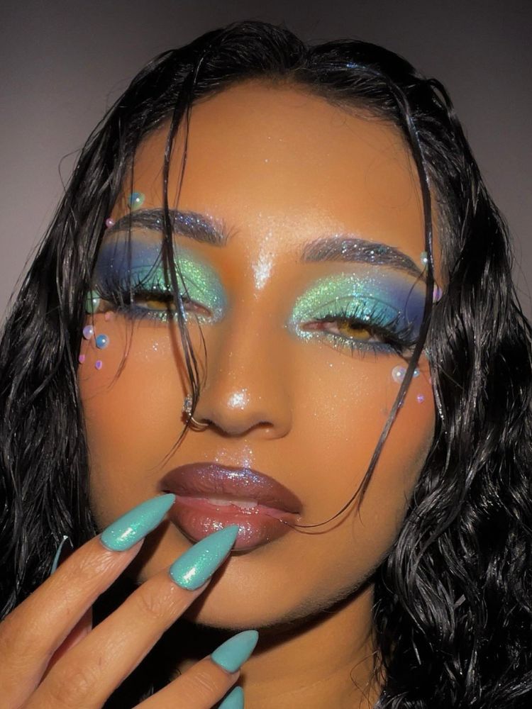 Mulher de pele morena com maquiagem azul com strass e pérolas