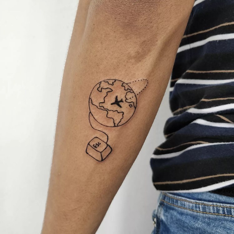 Tatuagem de viagem no braço de mundo com avião e tecla ESC