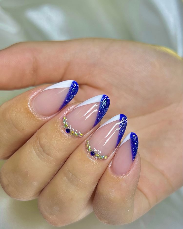 Unhas decoradas em tons de azul com francesinha e pedraria na cutícula
