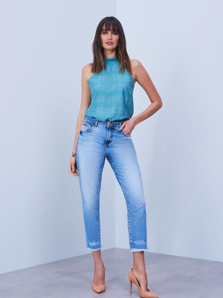 Mulher de pele clara com cropped verde e calça jeans mais curta