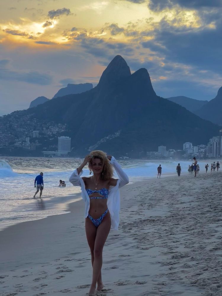 Larissa de biquíni azul e saída de praia branca na praia no Rio de Janeiro