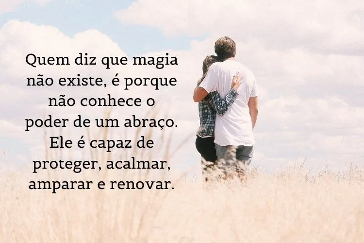 Foto de duas pessoas de costas se abraçando no campo e frase: Quem diz que magia não existe, é porque não conhece o poder de um abraço. Ele é capaz de proteger, acalmar, amparar e renovar.
