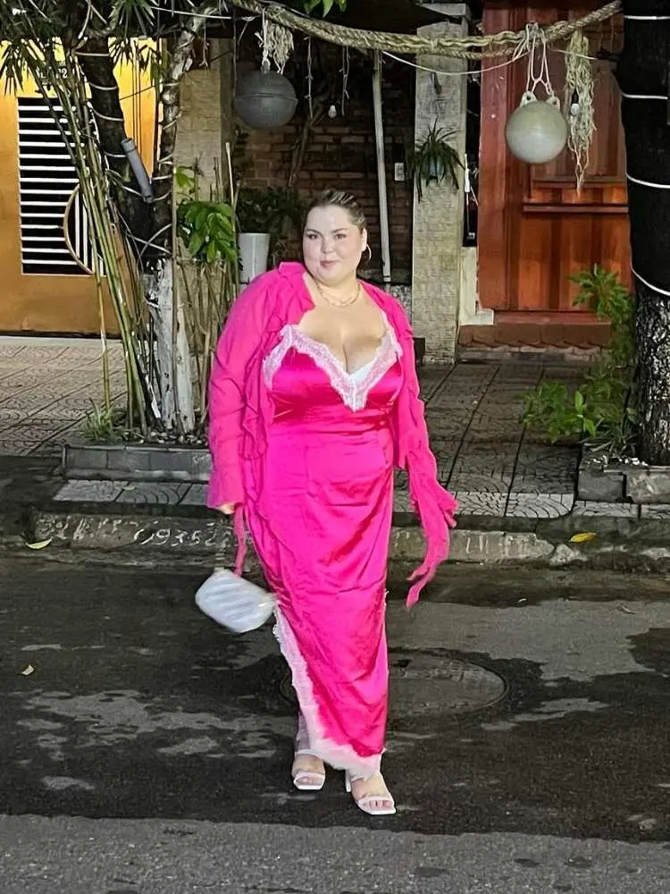 Mulher de pele clara usando slipdress rosa com cardigan rosa