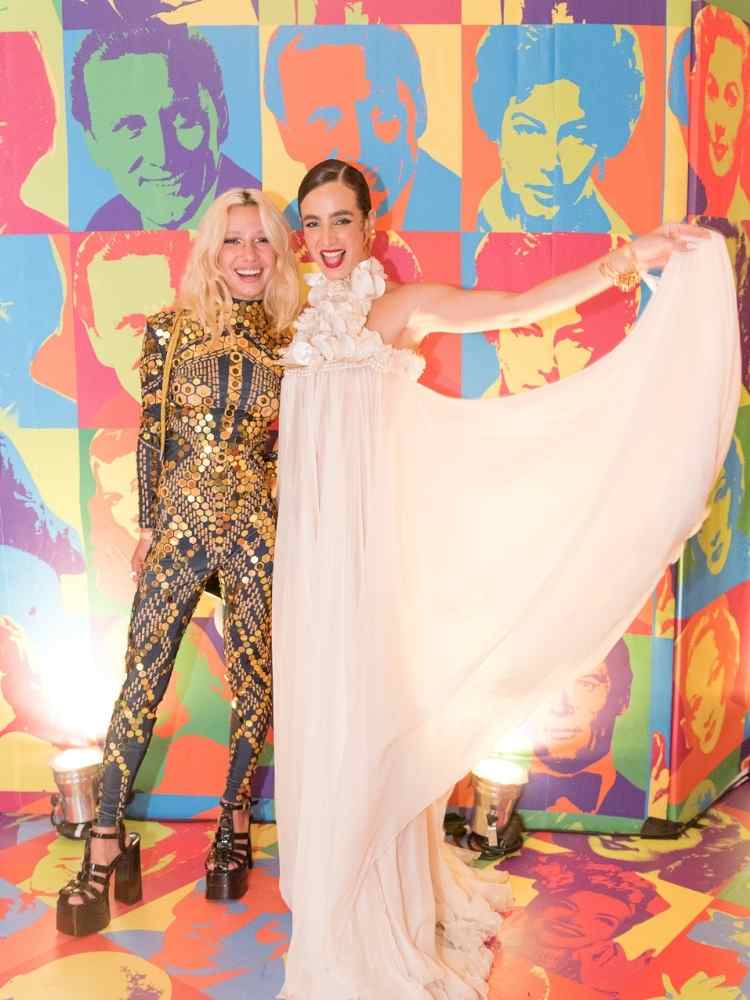 Chica Capeto, com look preto e dourado, e Julia Nolasco, com vestido solto claro, no Baile da Copa 2023.