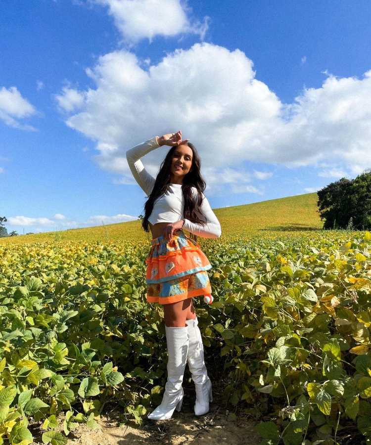 Menina com look de são joão, cropped branco + saia + bota branca