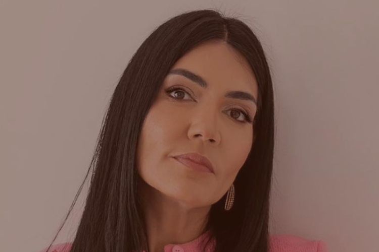 A imagem exibe Francine Prado do Desapego Legal de pele clara, cabelos lisos e longos, vestindo roupas rosas. Sua expressão serena complementa os brincos dourados discretos, enquanto o fundo neutro realça o destaque em seu rosto, transmitindo elegância e simplicidade.