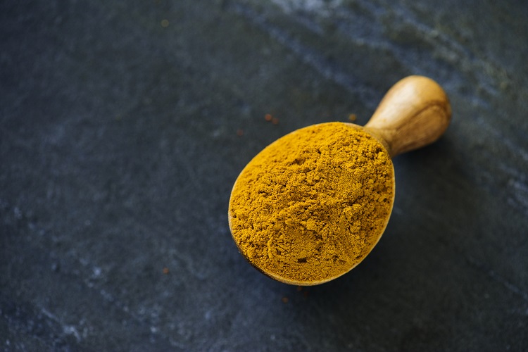Foto de colher de madeira com pó de açafrão-da-terra
