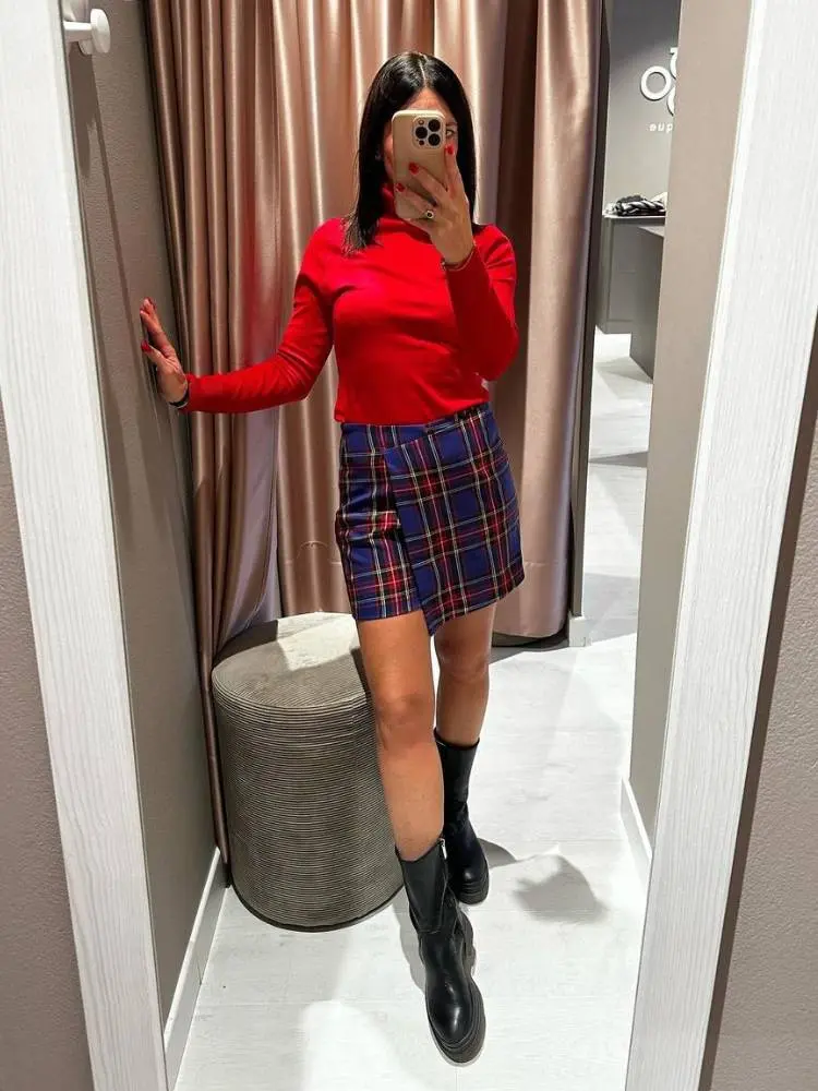 Mulher usa saia xadrez como sugestão de roupa vermelha para Natal