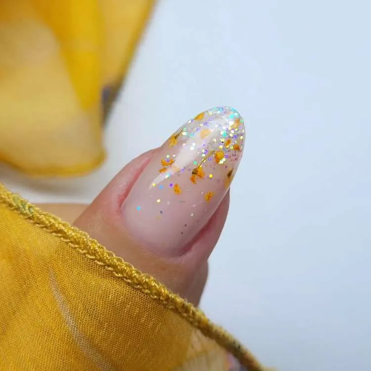 Unha almond decorada nas cores: bege natural, glitter e Desenho de flores minusculas amarelas
