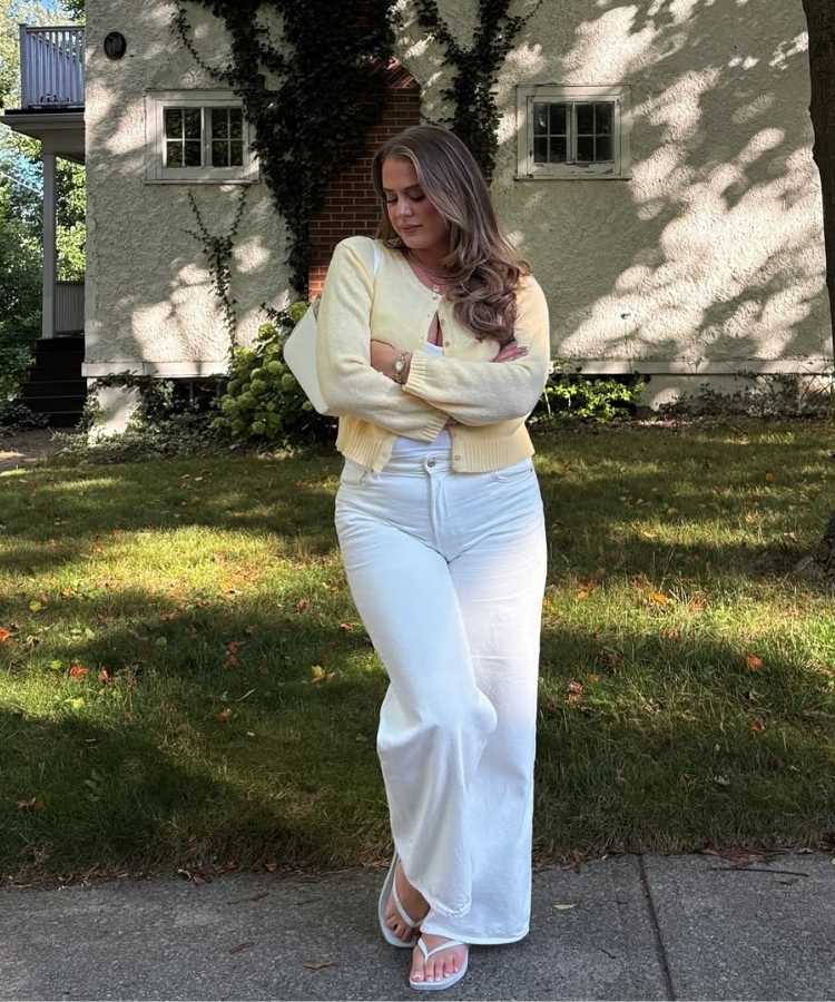 Foto de mulher usando calça denim na cor do ano de 2026 da Pantone com suéter amarelo