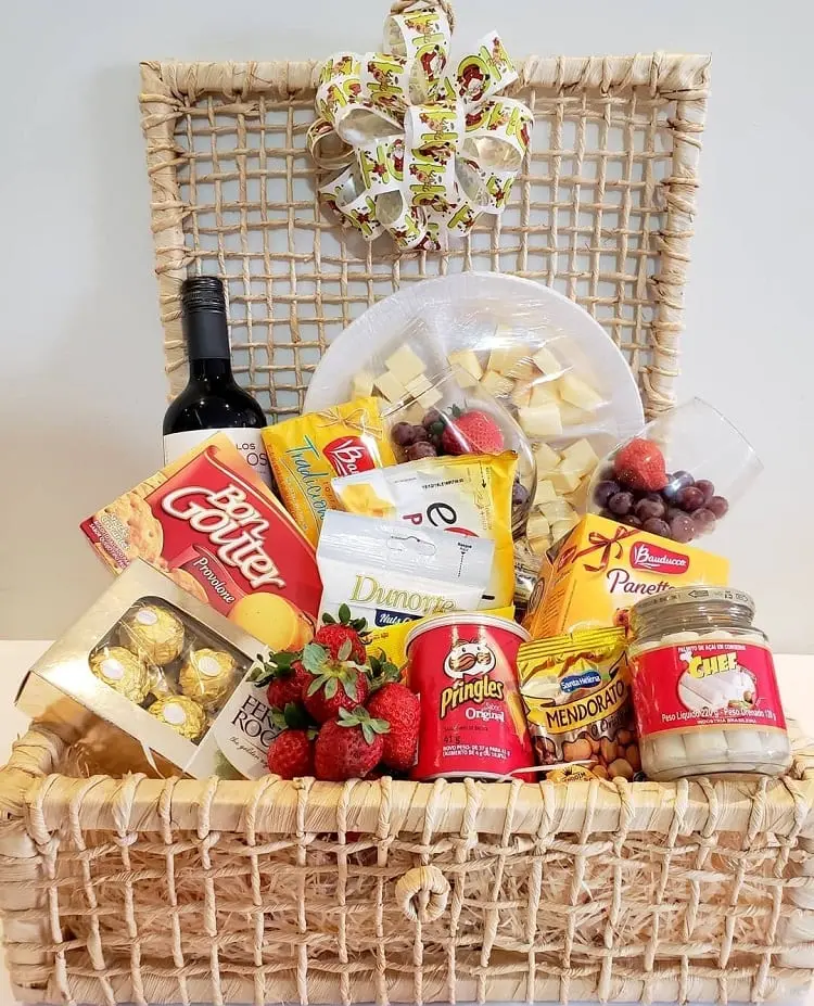 garrafa de vinho, tábua de queijos, taças, aperitivos, morangos e chocolate