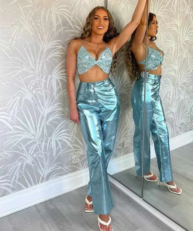Mulher com top brilhosos azul + calça metálica azul.