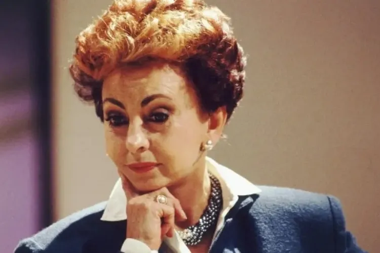 Foto de Odete Roitman com mão no queixo e camisa azul 