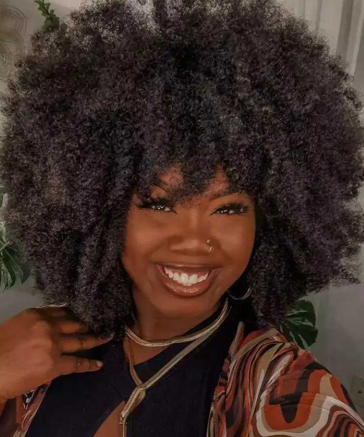 Mulher com corte de cabelo médio crespo franja assimétrica