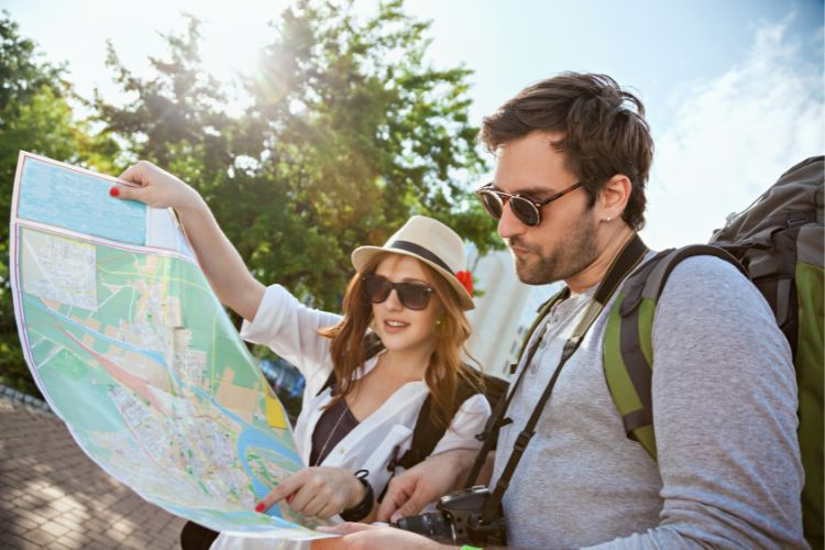 Foto de homem e mulher de pele clara turistando, olhando mapa 