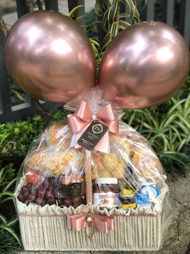 Cesta de chocolates diversos, pães e balões
