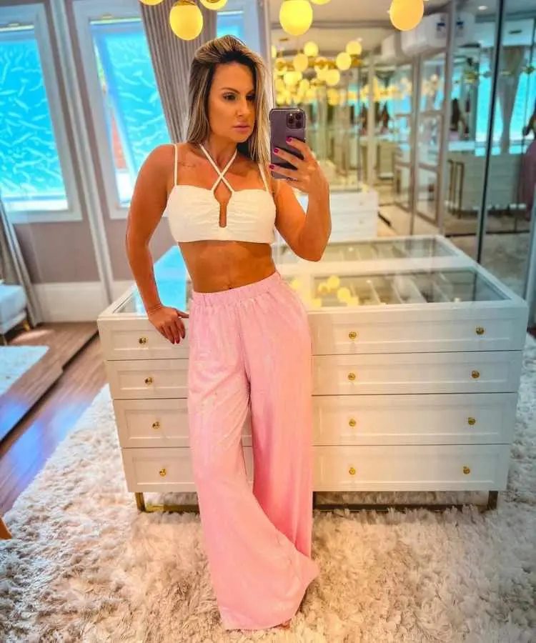 Mulher com calça rosa brilhosa e top branco.
