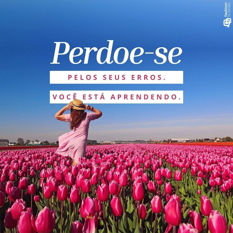 Mulher de vestido rosa e chapéu de palha caminha por campo de tulipas vibrantes sob céu azul. Texto central: “Perdoe-se pelos seus erros. Você está aprendendo.” Imagem inspiradora perfeita para promover frases de amor-próprio e reflexão pessoal.