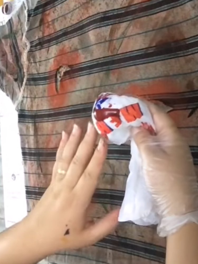 Mulher de pele clara usando sacola plástica com sangue falso para pintar camiseta 