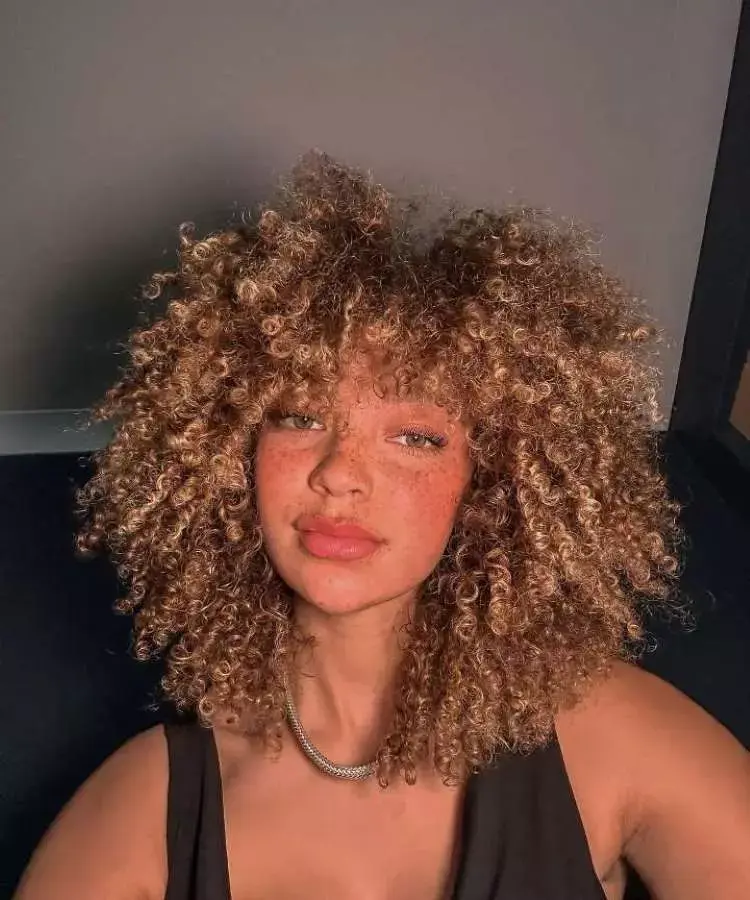 Mulher com corte de cabelo médio crespo franja irregular