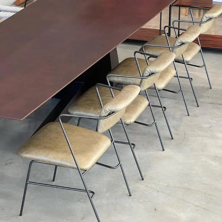 Chão de cimento queimado, mesa de madeira escura e cadeiras em couro bege e detalhes em aço