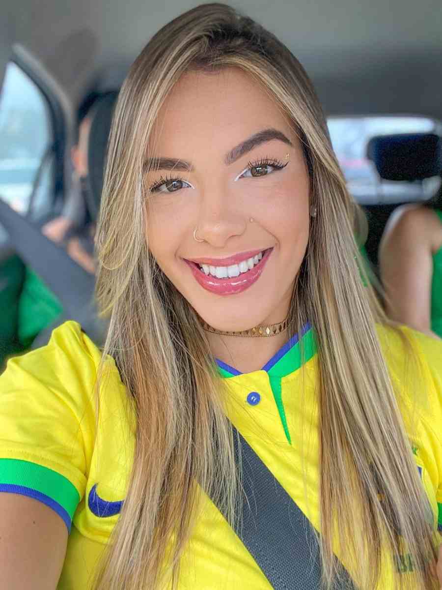 Selfie de mulher sentada no banco do carro usando camisa amarela do Brasil.